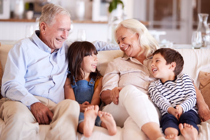 Long Term Care Insurance by Craven Financial 1 White senior couple and their grandchildren sitting on a sofa together smiling at each other 1162298071 727x484 jpeg